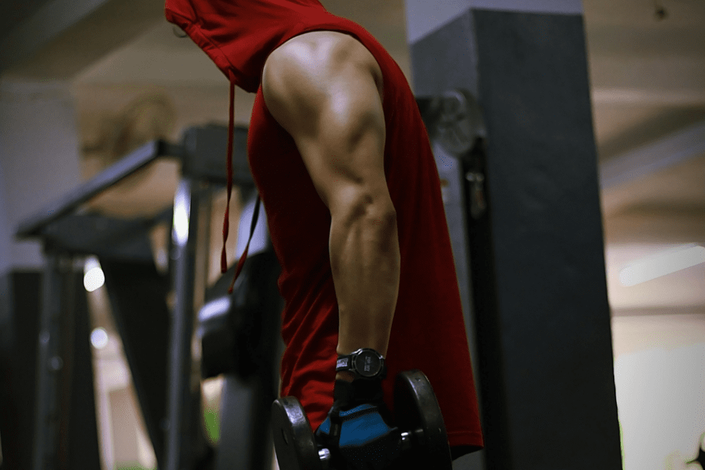 man in hoodie holding dumbbell